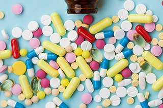 Pile of colorful drug pills of different sizes on a blue background.