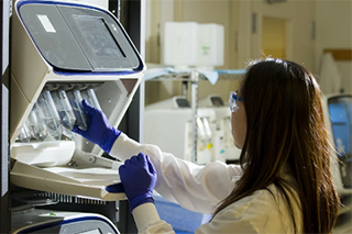 Female scientist using a machine in a lab to carry out a research experiment.