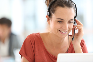 Smiling female customer service contact center employee using data from Minitab Connect to help a client over the phone.