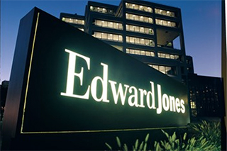 Lit up Edward Jones Office entrance sign outside of the office at dusk.