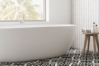 Modern bathroom with bathtub, stool, and vanity and black and white decorative tiles.