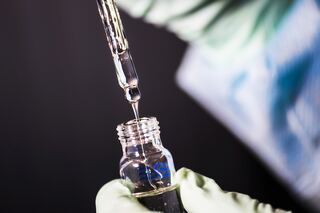 Closeup of a vaccine being drawn with blurred hands of a doctor.