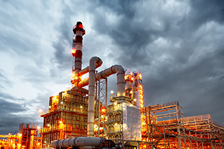 Lit-up oil refinery with cloudy skies.