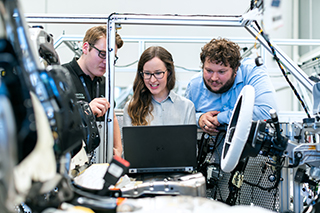 Three engineers using manufacturing solutions software to analyze the quality of various auto parts.