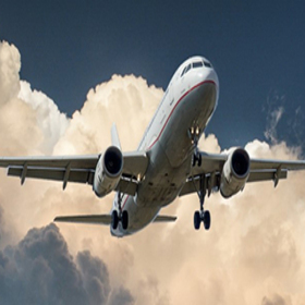 Airplane ascending in the sky with a cloud in the background.