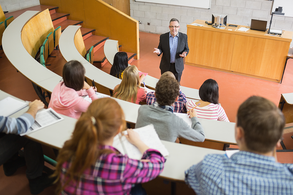Male professor teaching statistics to a lecture full of undergraduate students.