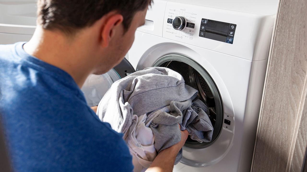 Man loading washer with clothes.