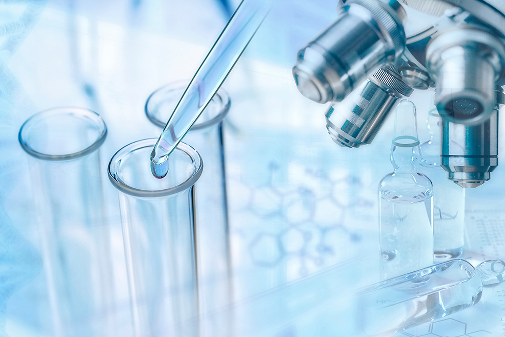 Pipette dropping liquid into three test tubes with a microscope on the side.