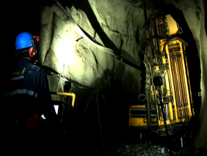 Miner in safety gear monitoring large mining machinery