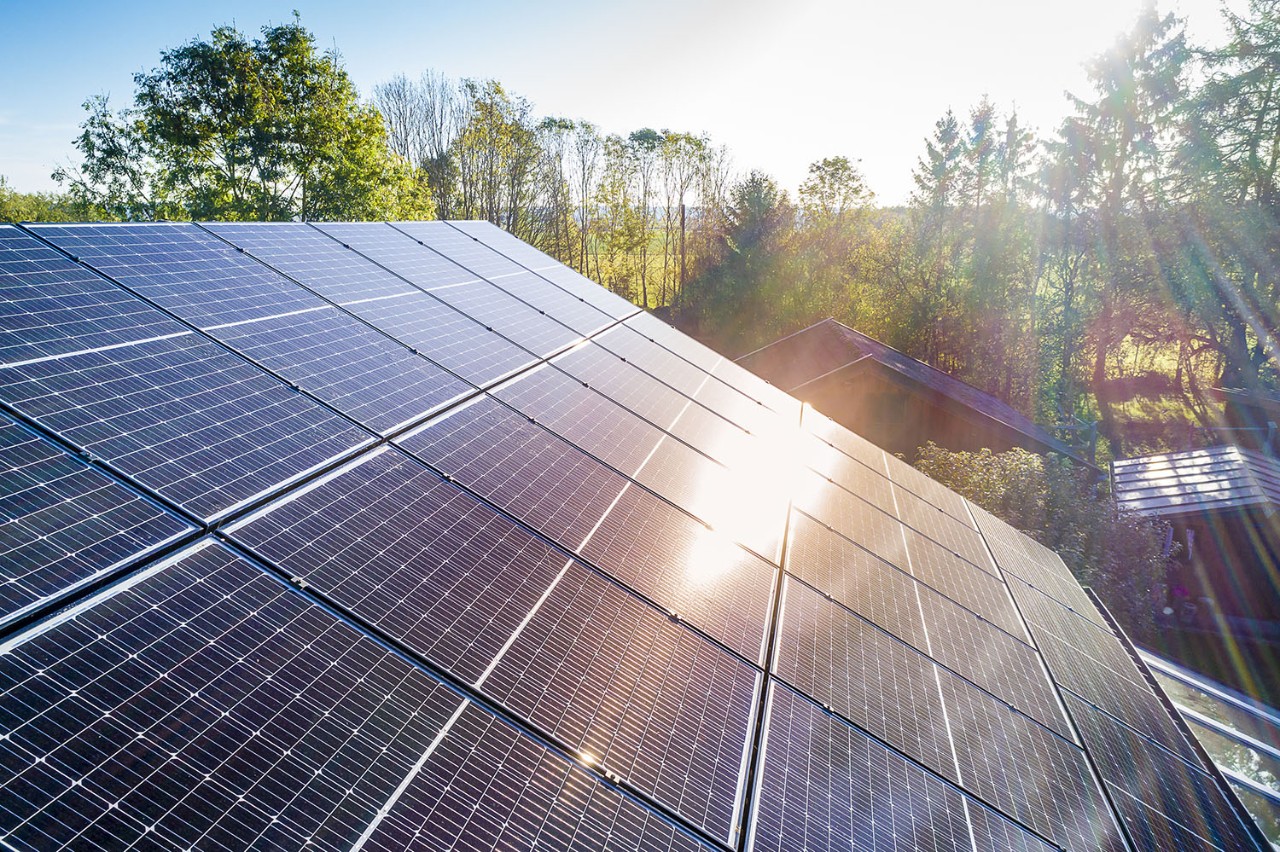 Solar panels and sunlight reflextions on the roof against blue sky background. Concept clean power energy.