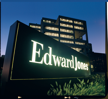 Illuminated sign of Edward Jones in front of an office building.